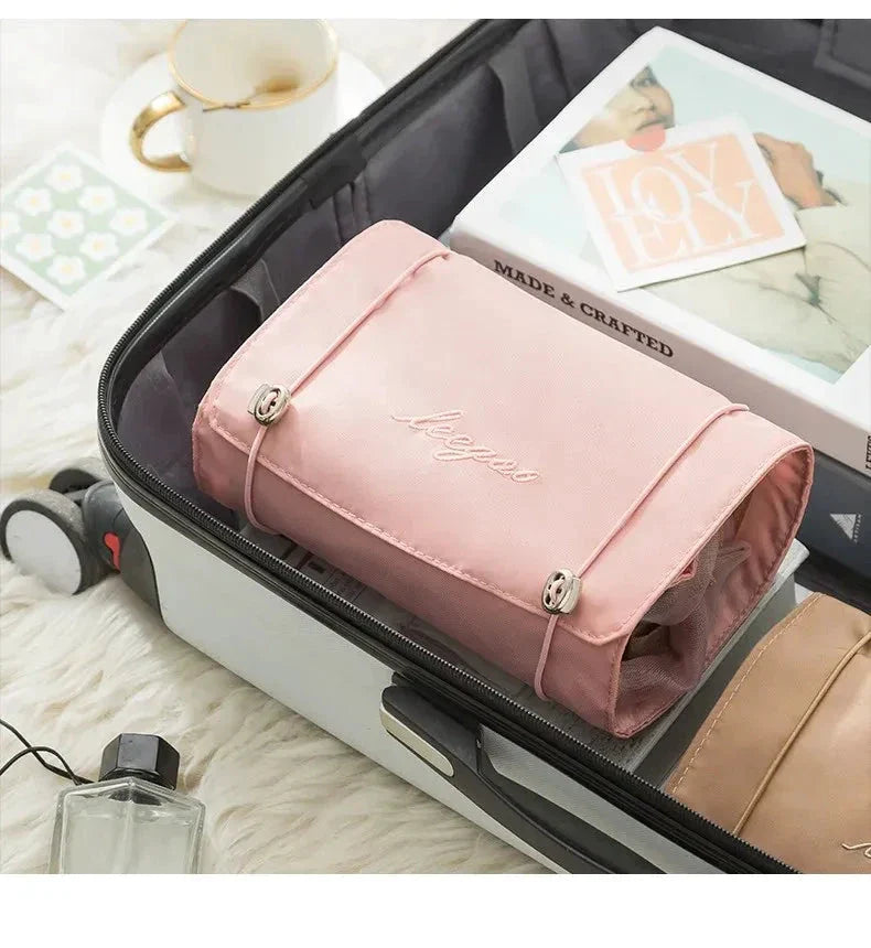 Pink travel organizer bag folded inside a suitcase alongside other packed items.